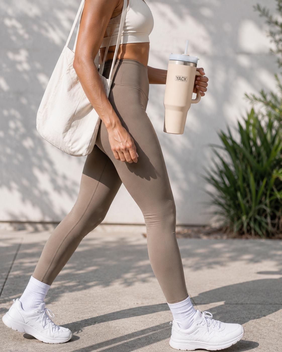 Sportive marchant avec un gobelet isotherme Yack rose pale 1,2 L à la main dans un environnement de salle de sport.